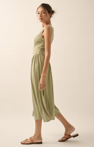 Woman wearing a green dress standing against a plain background