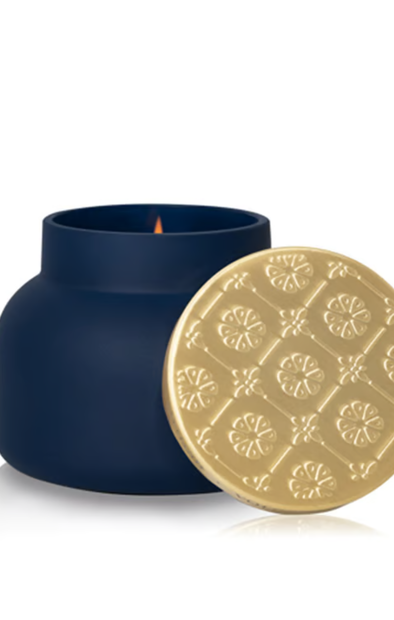 A navy blue matte jar candle with a matching decorative gold lid leaning against it on a white background.