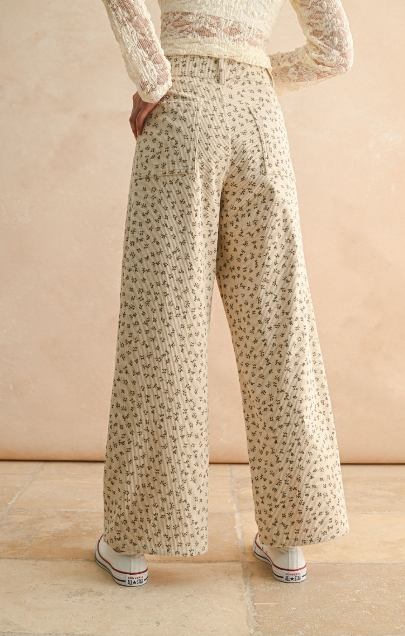 Person wearing floral pants and a light top against a beige background