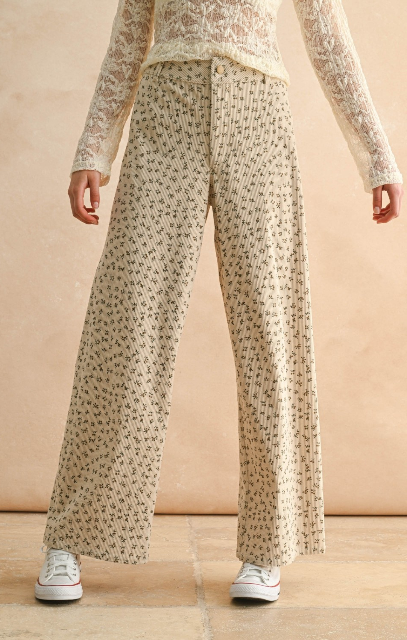Person wearing a floral top and patterned pants on a beige background