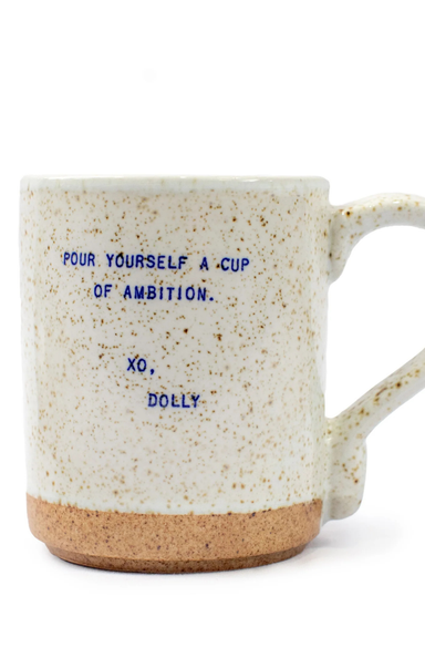 Speckled mug with text 'Pour yourself a cup of ambition. XO, Dolly' on a white background