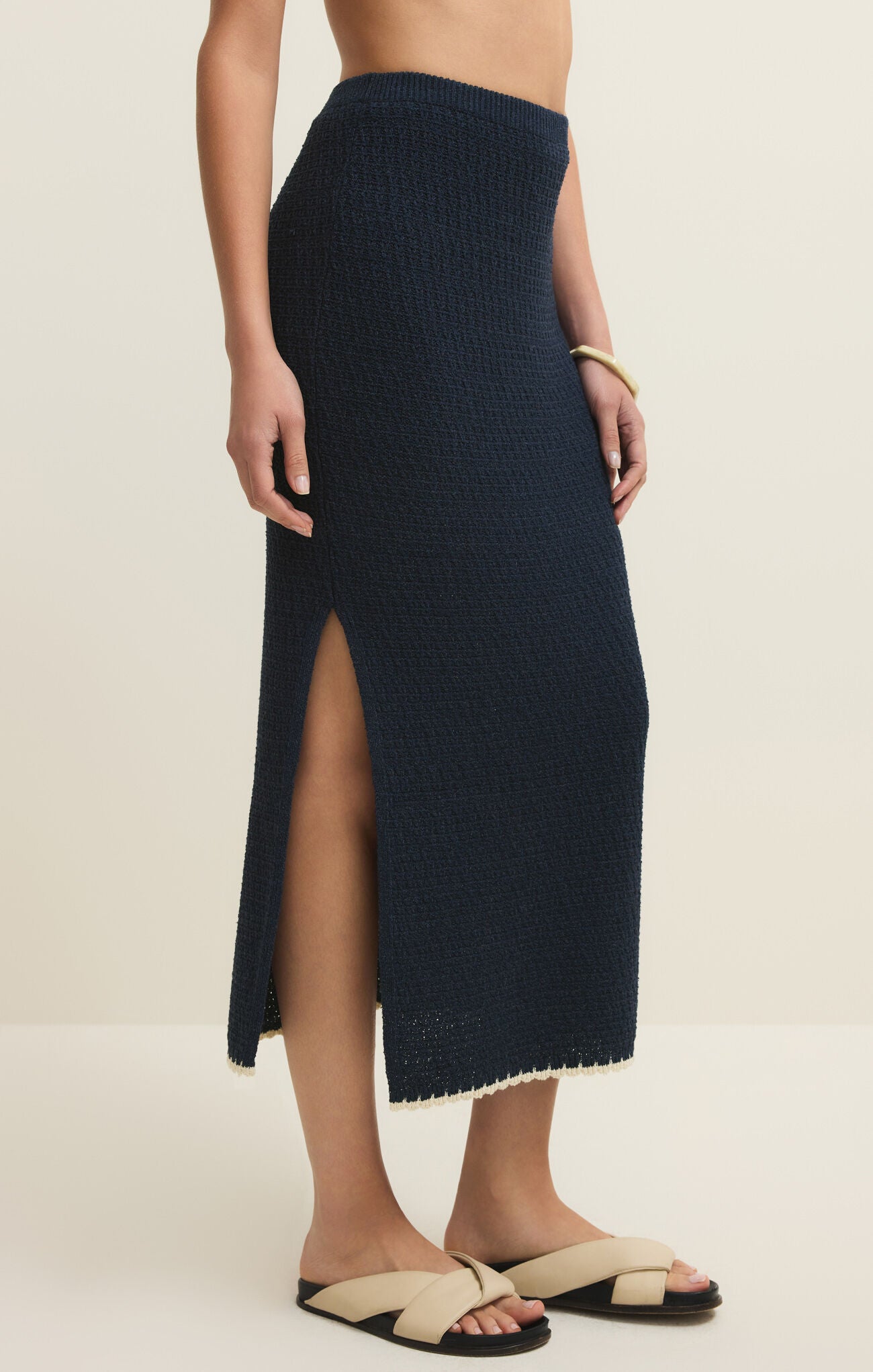 Navy knit skirt with a high slit worn by a person on a beige background