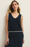 Woman wearing a navy blue sleeveless dress with white trim against a plain background