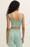 Woman wearing a green sports bra and leggings set on a beige background