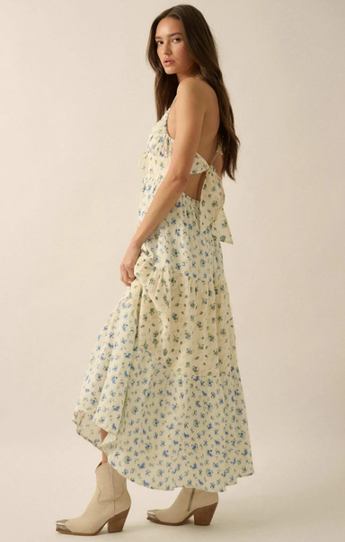 Woman wearing a floral dress with beige boots on a plain background