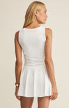 Woman wearing a white sleeveless dress against a beige background