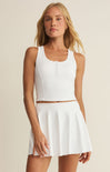 Woman wearing a white sleeveless top and skirt set on a beige background