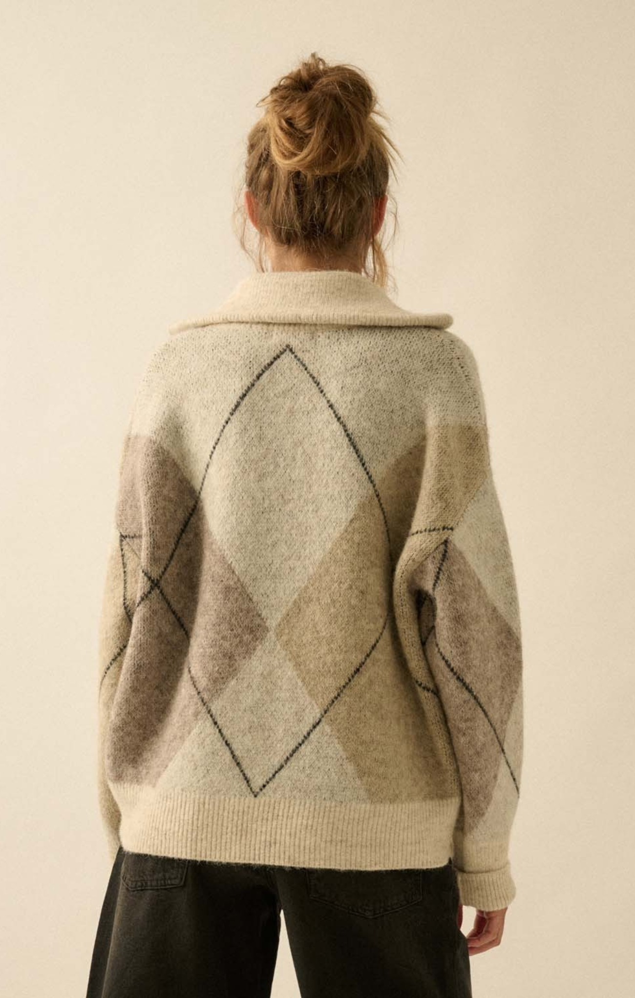 Person wearing a patterned sweater with a neutral background