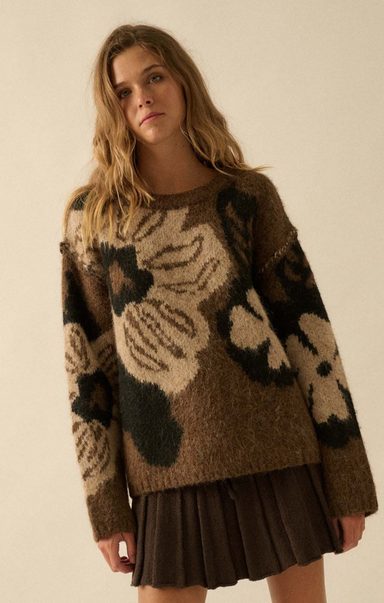 Woman wearing a brown sweater with abstract patterns on a plain background