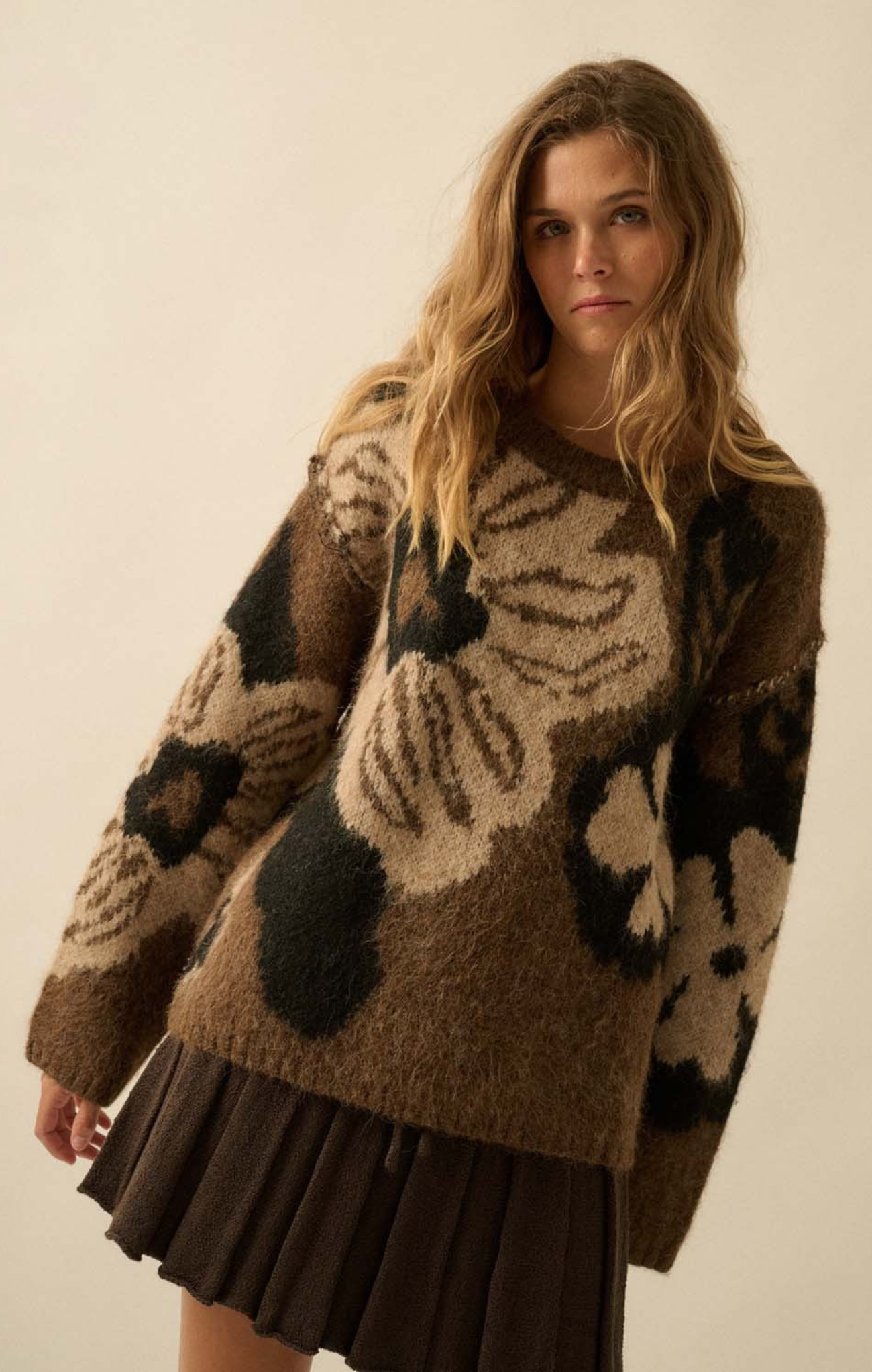 Woman wearing a brown patterned sweater against a plain background