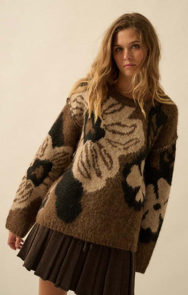 Woman wearing a brown patterned sweater against a plain background