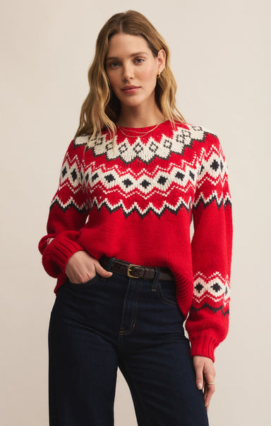 Woman wearing a red sweater with a pattern, standing against a plain background