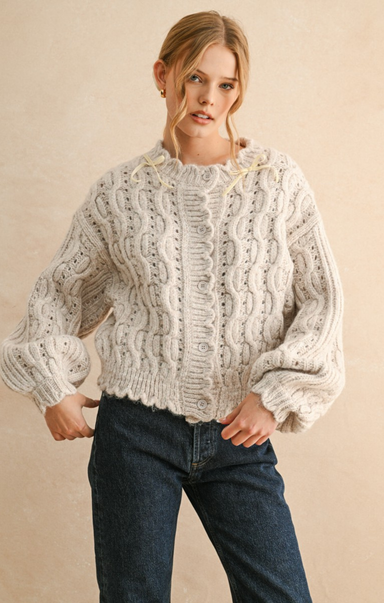Woman wearing a white knitted sweater and blue jeans on a beige background