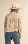 Person wearing a beige striped shirt, blue jeans, and a white hat on a beige background