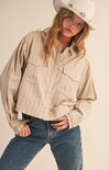 Person wearing a beige striped shirt, blue jeans, and a white cowboy hat on a plain background