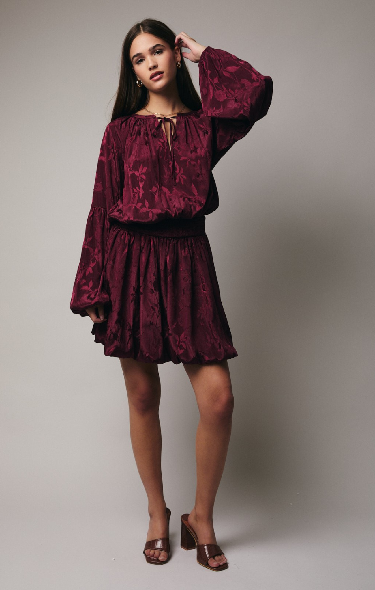Woman wearing a burgundy floral dress against a neutral background