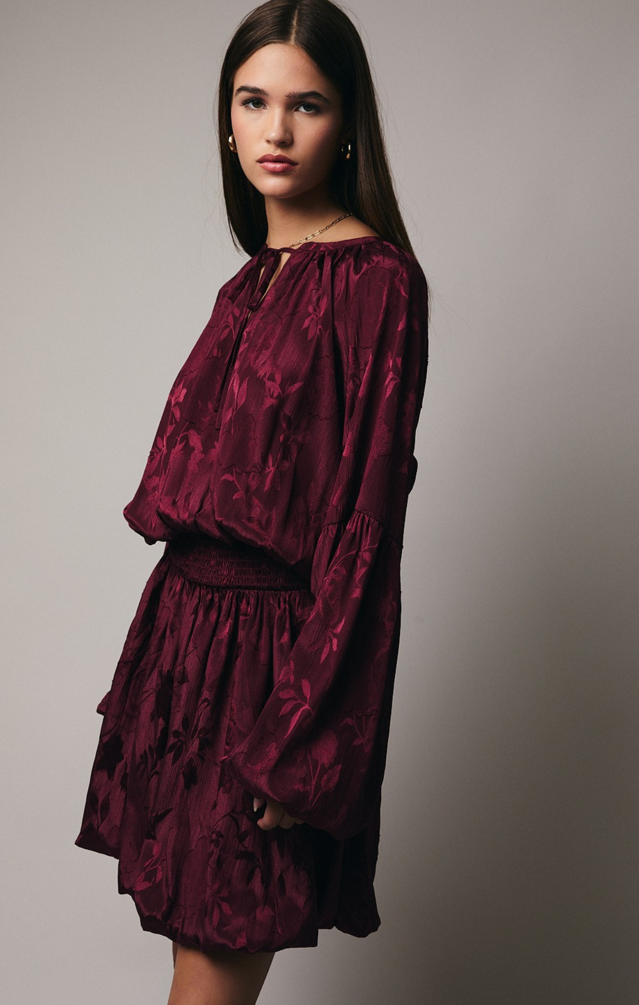 Woman wearing a burgundy dress against a plain background