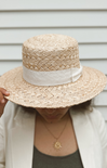 Person wearing a straw hat with a white band against a neutral background