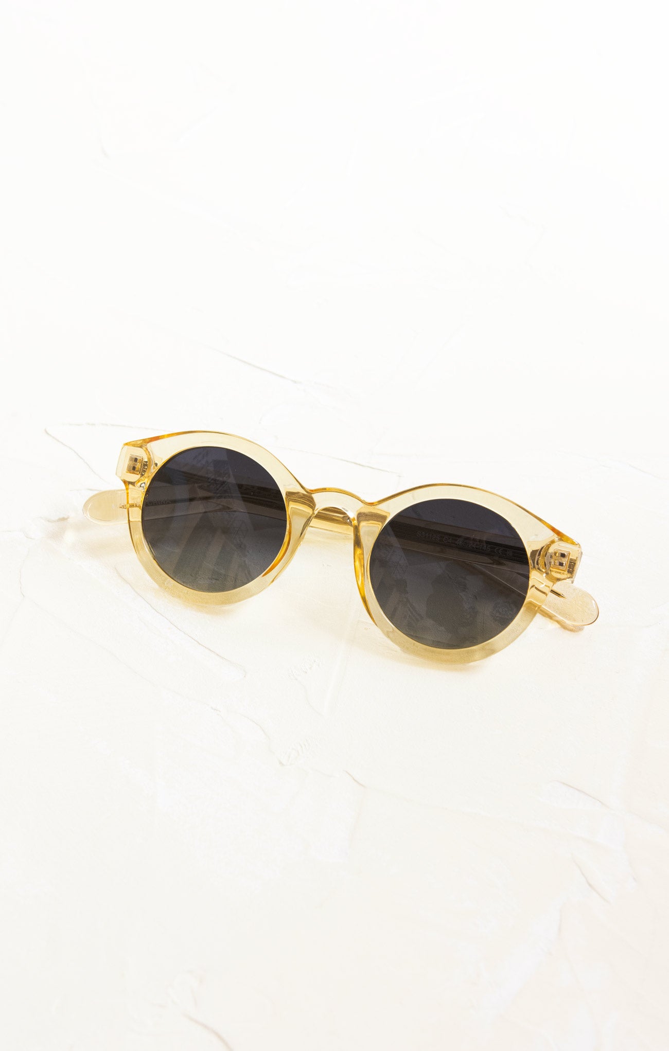 Gold-framed sunglasses with dark lenses on a white background