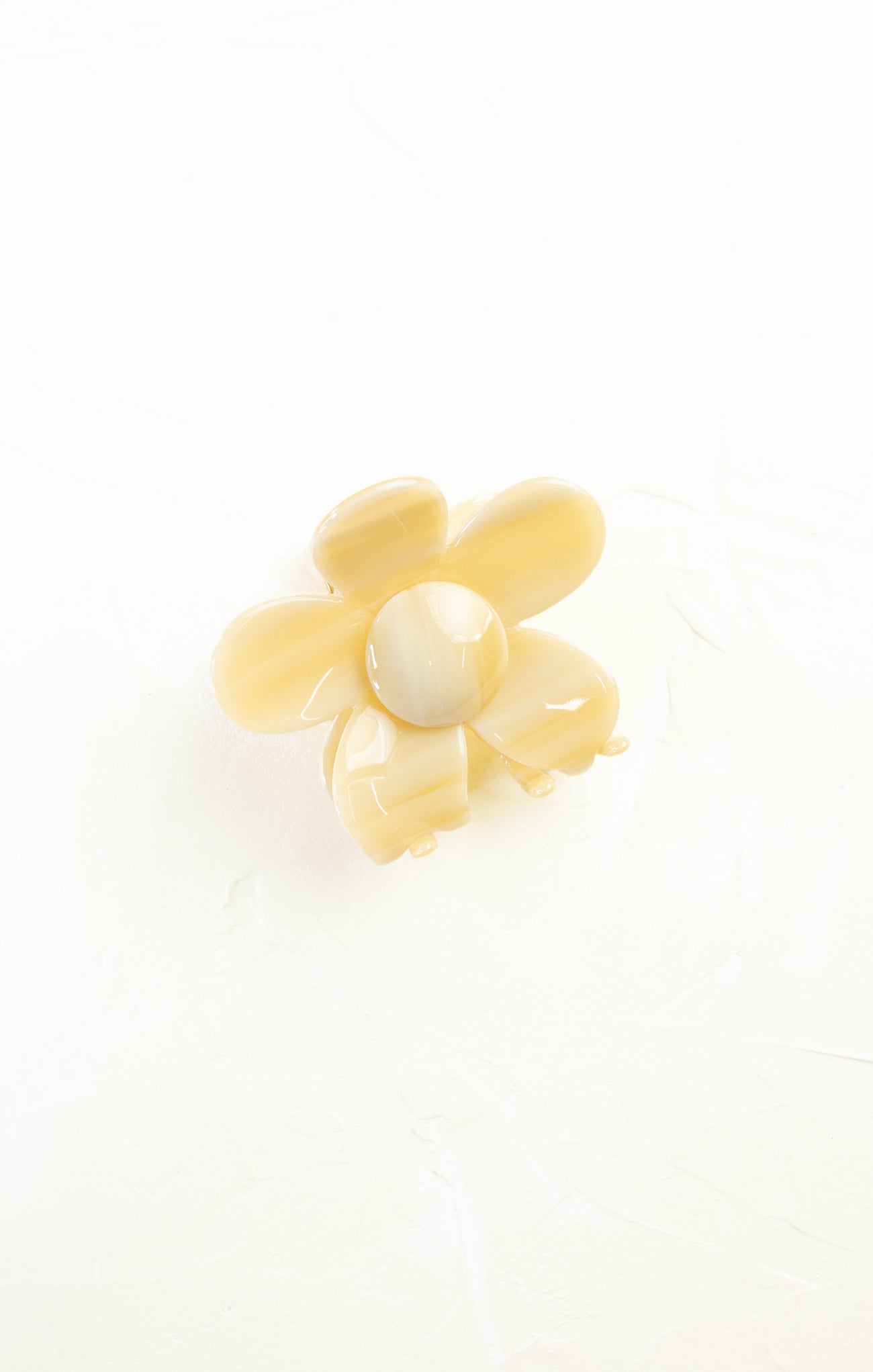 Yellow flower-shaped object with a central pearl on a white background