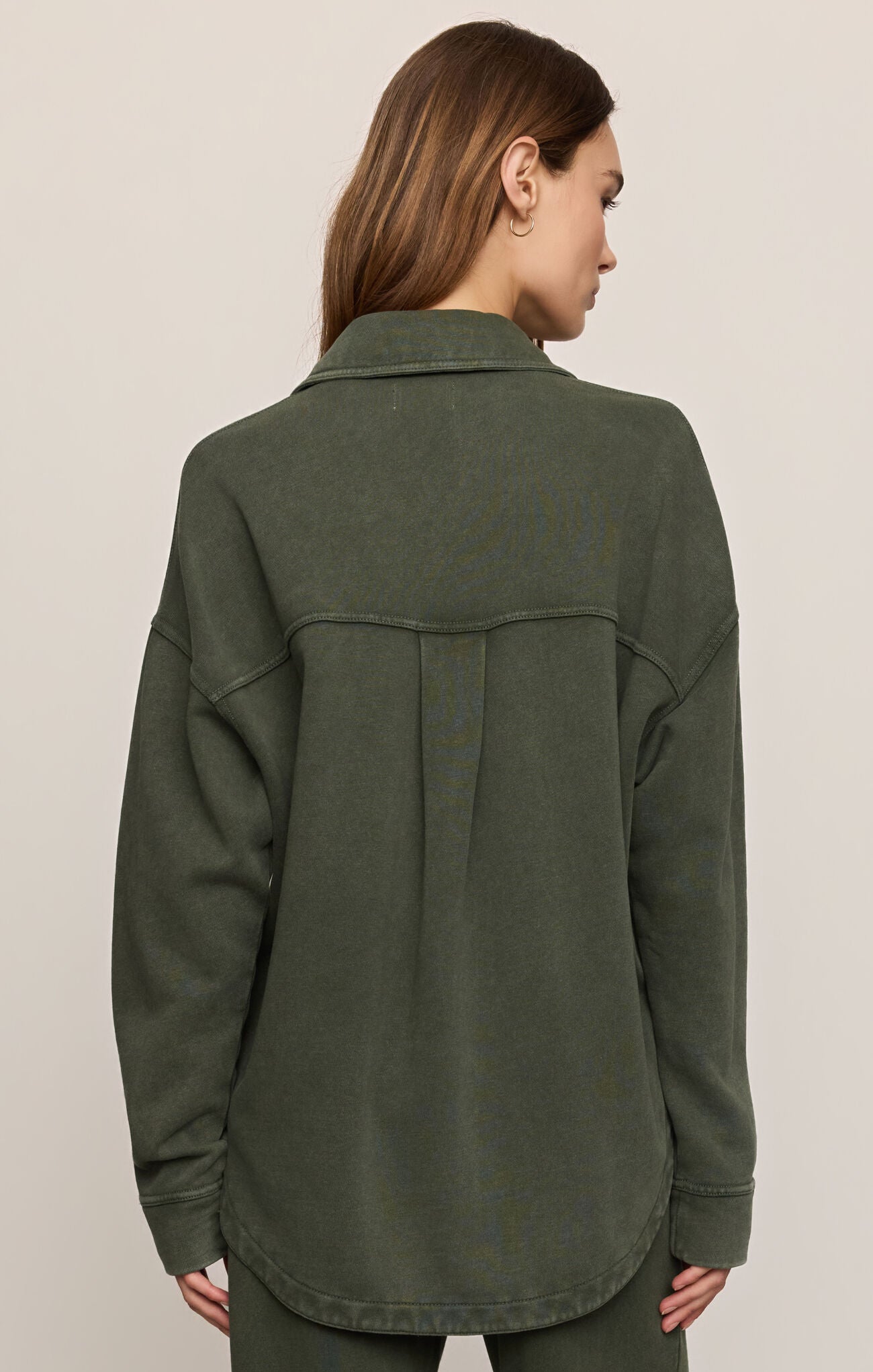 Person wearing a green jacket on a plain background