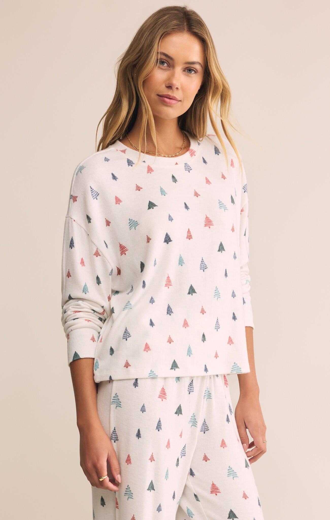 Woman wearing a white long-sleeve top with colorful geometric pattern on a beige background