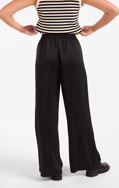 Person wearing a striped top and black wide-leg pants on a white background