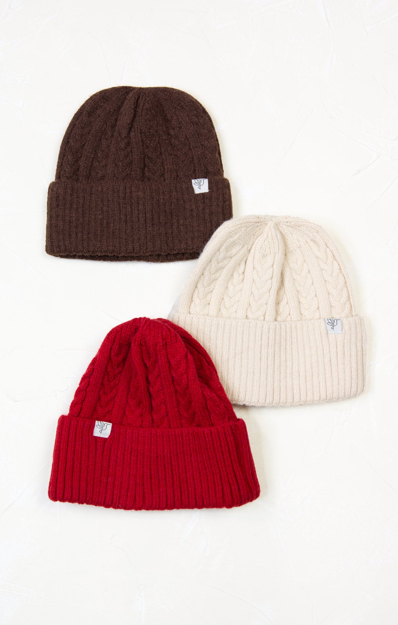 Three knit beanie hats in brown, red, and beige on a white background
