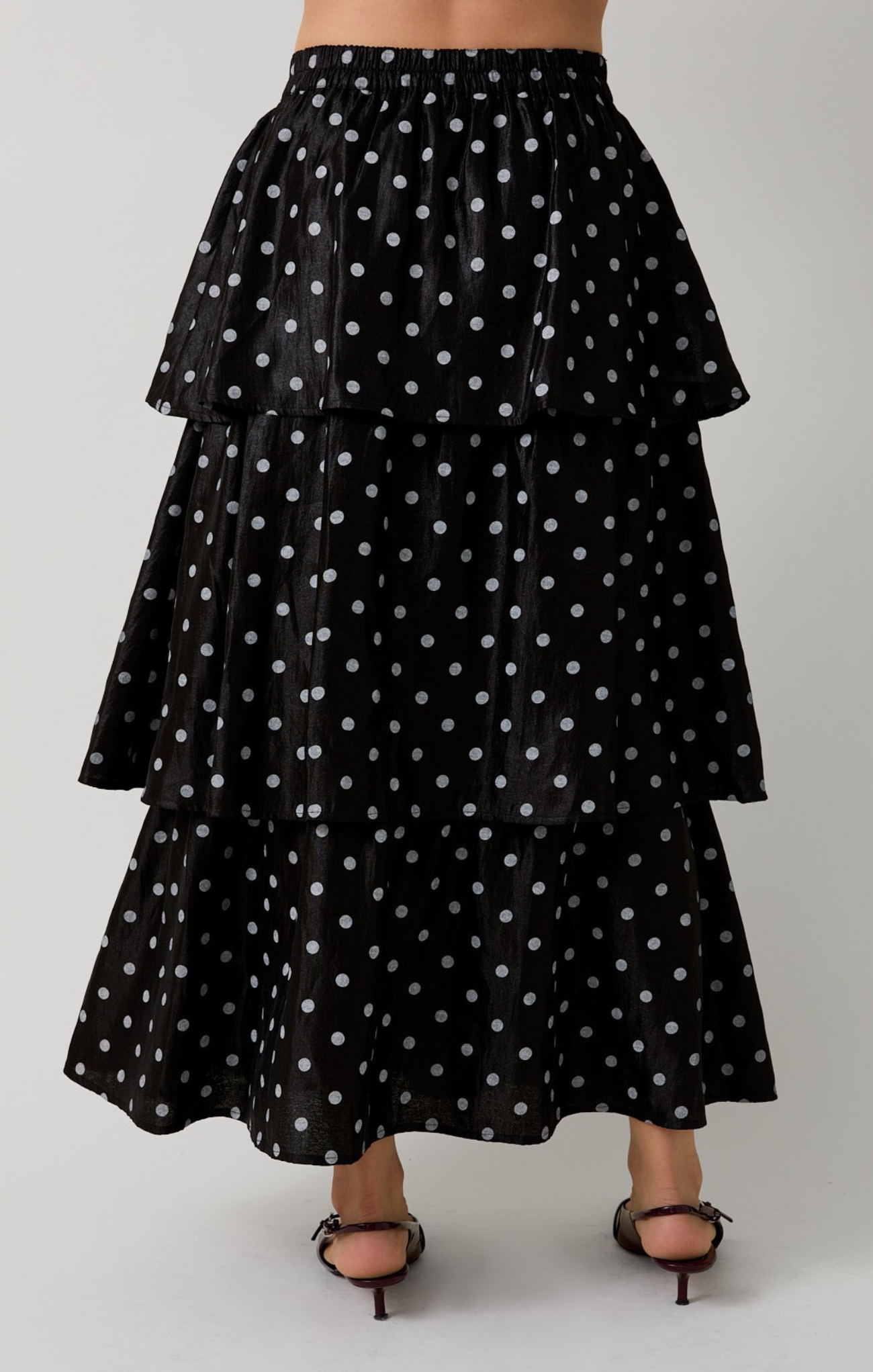 Black tiered skirt with white polka dots on a plain background