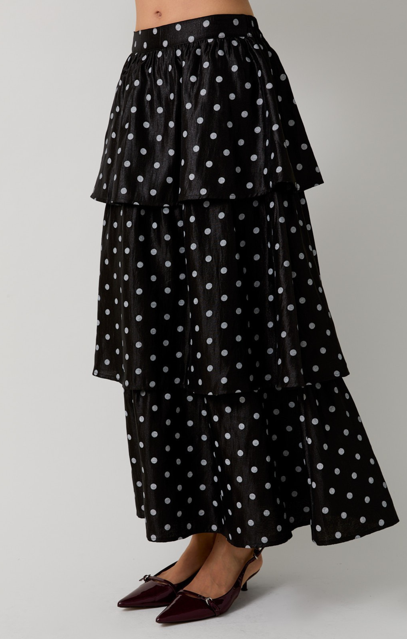 Black tiered skirt with white polka dots on a gray background