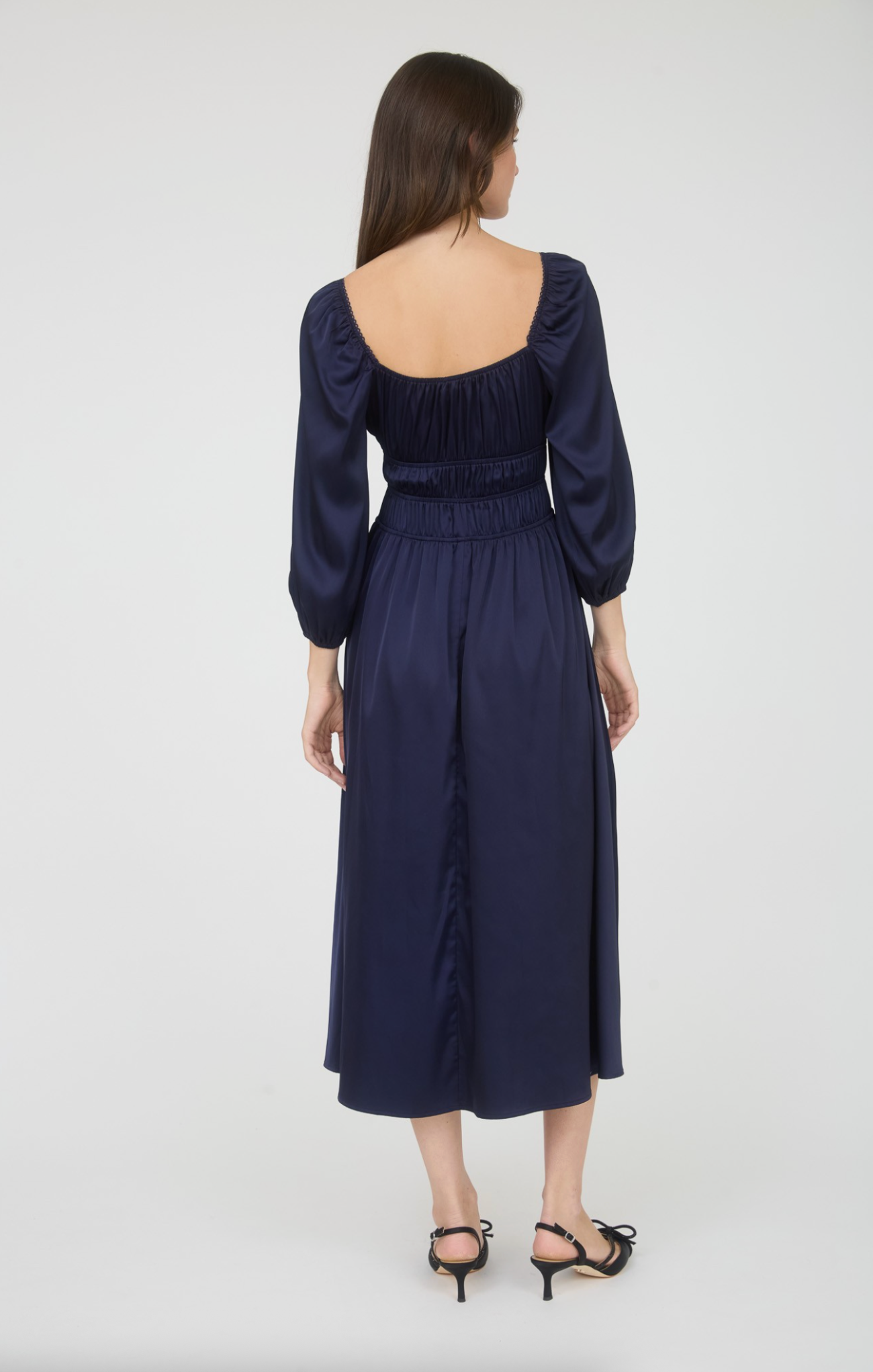 Woman wearing a navy blue dress with long sleeves on a white background