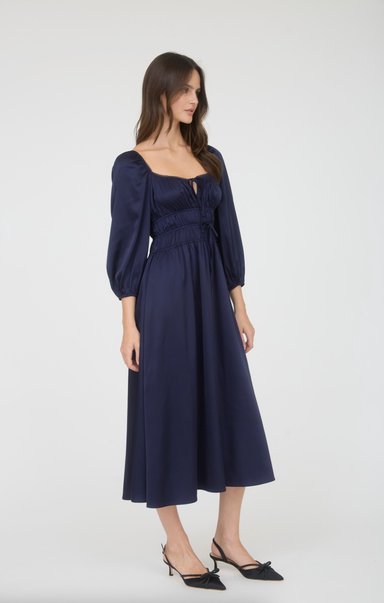 Woman wearing a navy blue dress with long sleeves on a white background