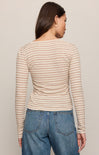 Woman wearing a striped long-sleeve top and blue jeans against a plain background