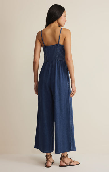 Woman wearing a blue jumpsuit on a beige background