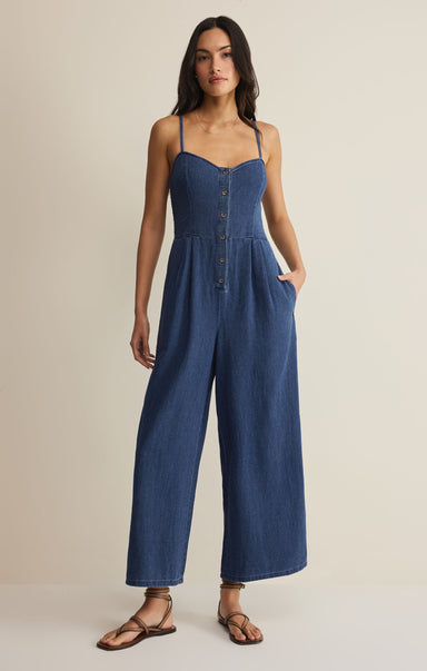 Woman wearing a blue jumpsuit on a beige background