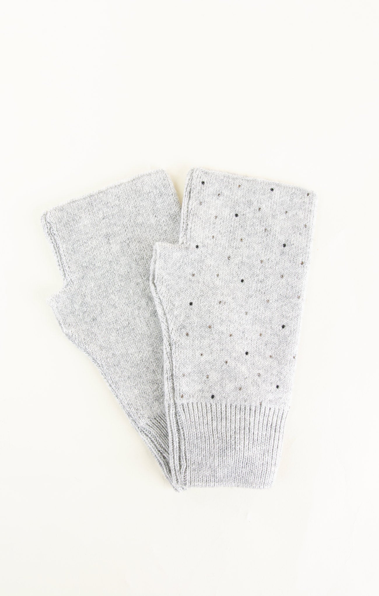 Gray knitted leg warmers with small black dots on a white background
