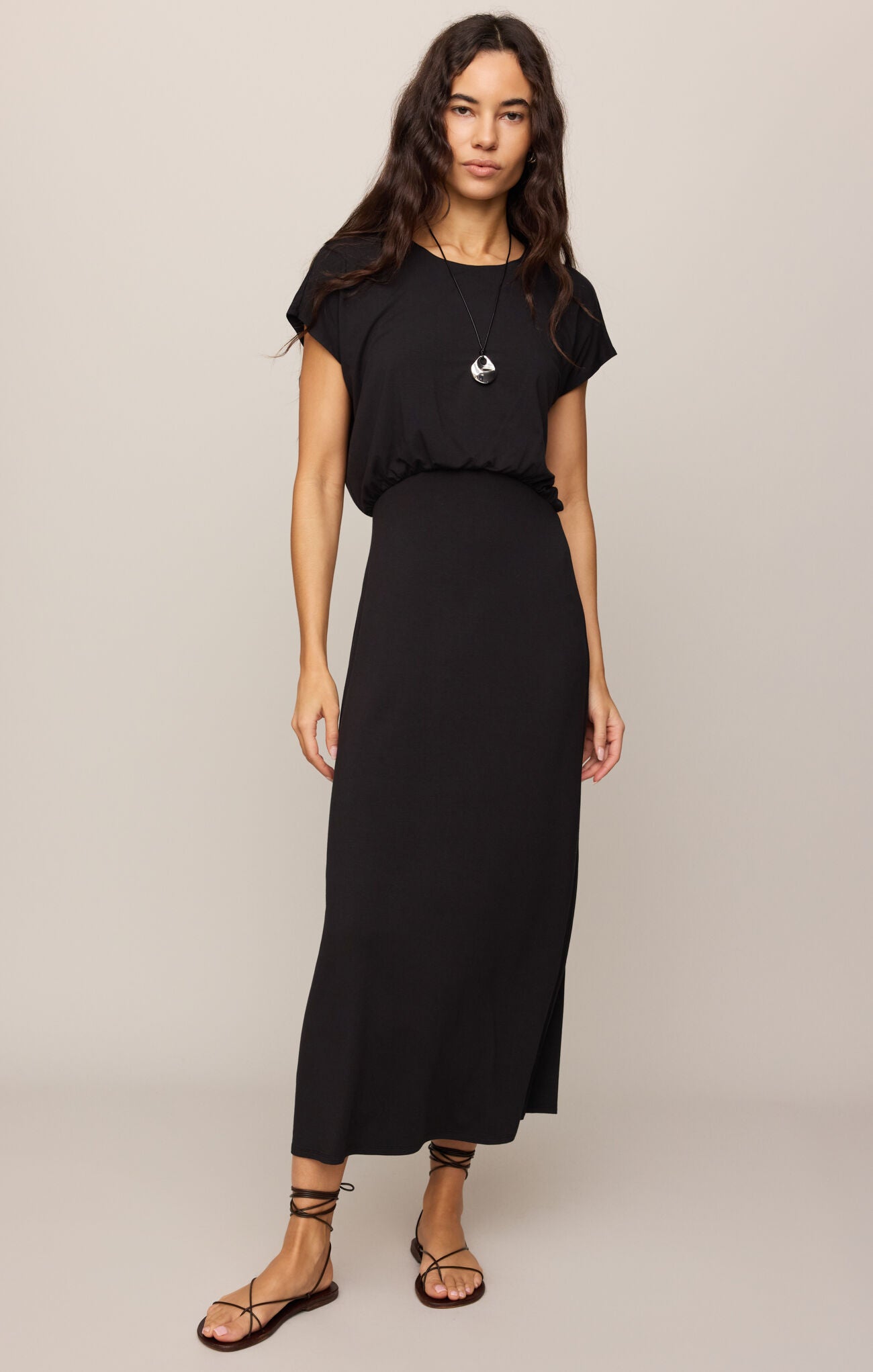 Woman wearing a black outfit with a logo on a plain background