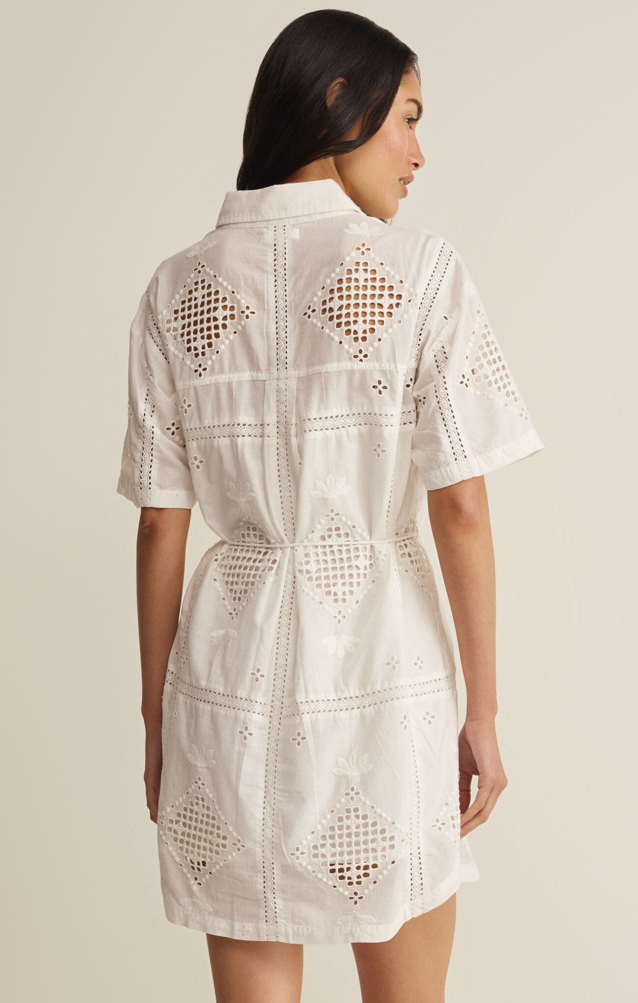 Woman wearing a white lace dress against a neutral background