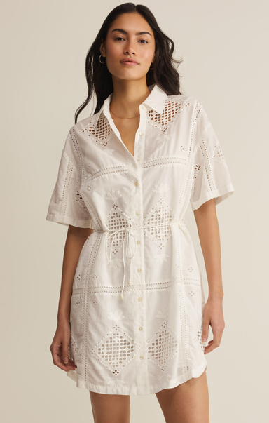 Woman wearing a white lace dress against a beige background