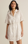 Woman wearing a white lace dress against a beige background