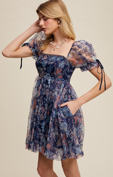 Woman wearing a floral dress with puff sleeves on a beige background
