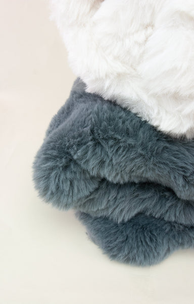 Stack of blue and white fluffy blankets on a light background
