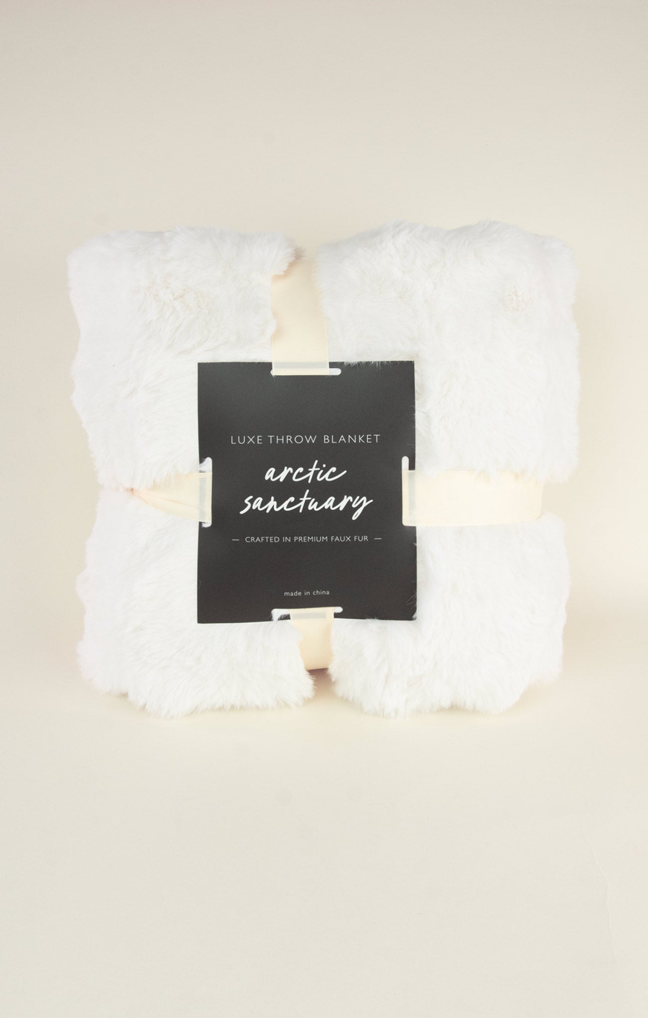 White throw blanket with a label on a beige background