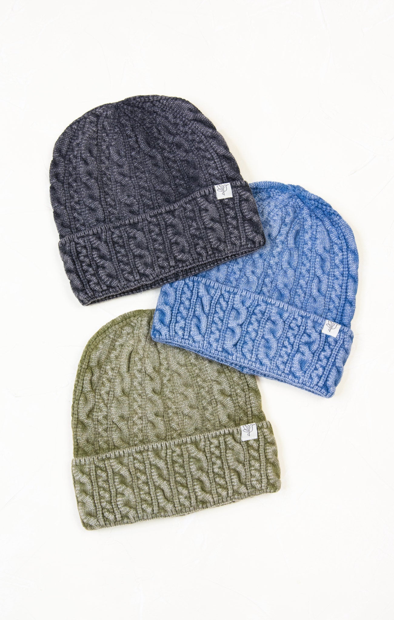 Three knit beanie hats in gray, blue, and green on a white background