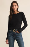 Woman wearing a black sweater and blue jeans on a beige background