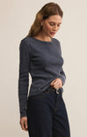 Woman wearing a dark blue textured sweater and jeans on a beige background
