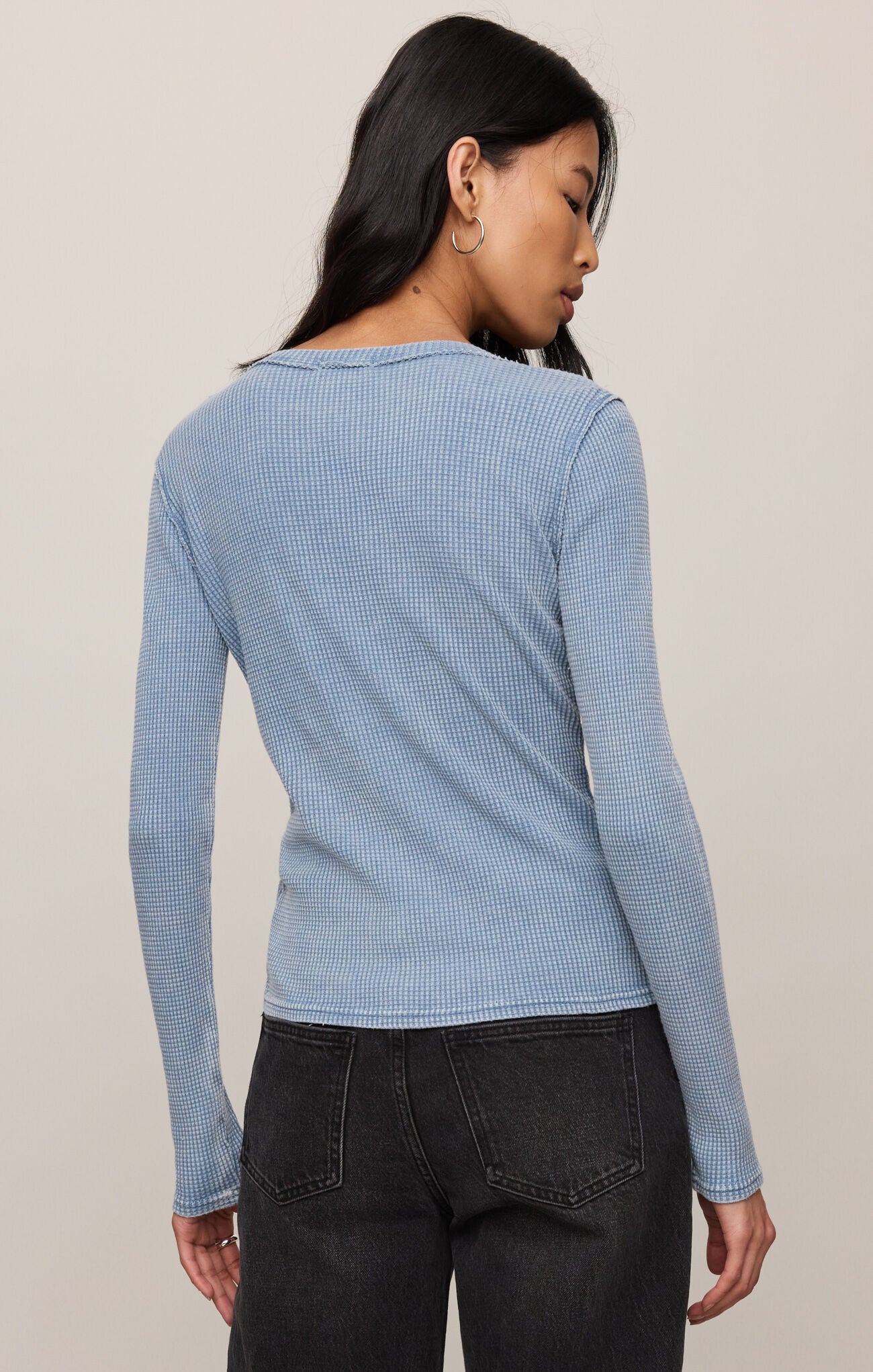 Woman wearing a light blue textured long-sleeve top against a neutral background