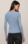 Woman wearing a light blue textured long-sleeve top against a neutral background