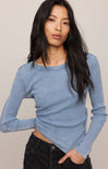 Woman wearing a blue long-sleeve top against a plain background