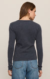 Woman wearing a dark blue textured sweater and jeans on a beige background